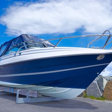 Blue and white boat docked on land under a cloudy sky.