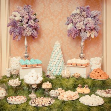 Elegant dessert table with pastel treats and lilac flower arrangements.
