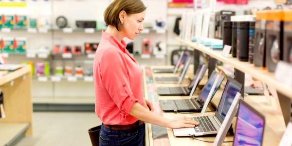 Mujer revisando laptops en tienda de tecnología.