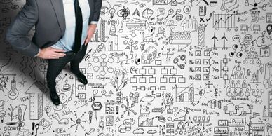 Man in suit standing among complex business strategy sketches and charts.