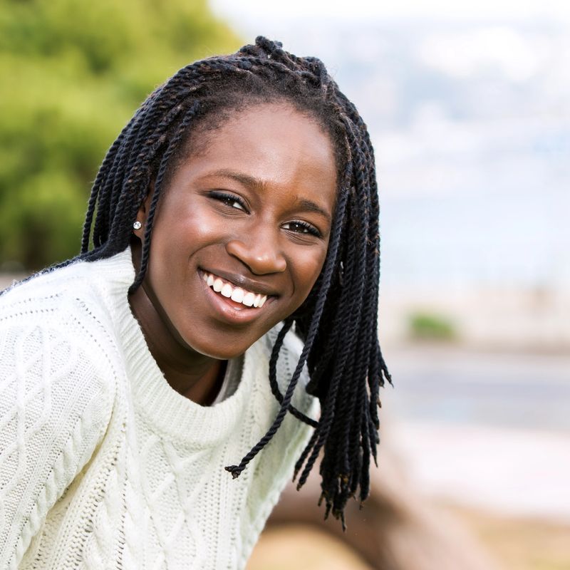 Close up outdoor portrait of attractive afro american teen girl with long braided hair.