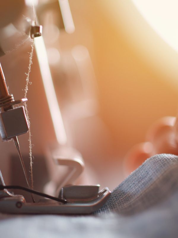 Close-up of a sewing machine needle with thread and fabric.