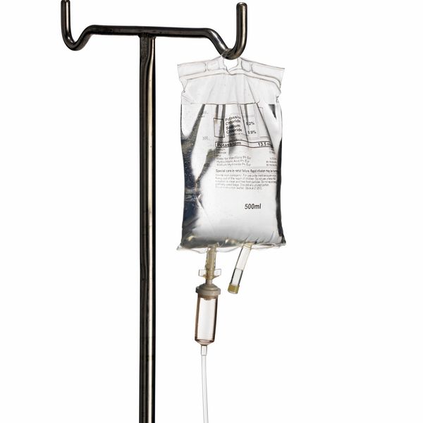 A medical IV drip bag hanging on a metal stand.
