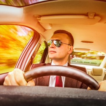Man driving car with sunglasses on a bright day.