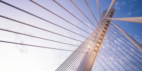 Close-up of a cable-stayed bridge tower with cables against blue sky.