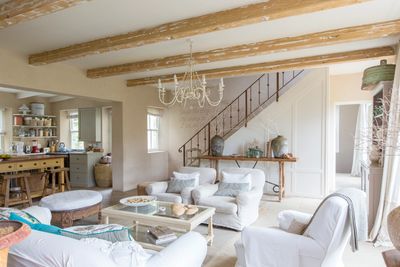 A living room with white sofas and oak beams
