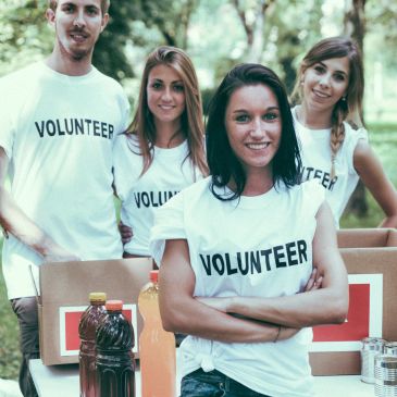 Group of volunteers smiling at an outdoor event.