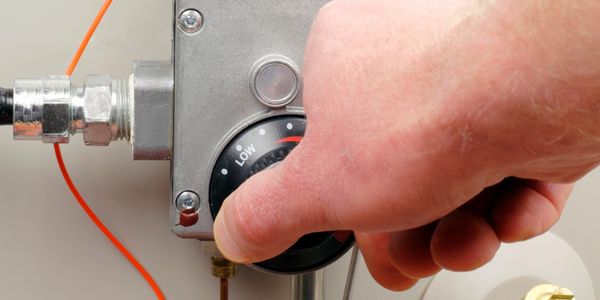 Hand adjusting a gas control valve on a heating system.
