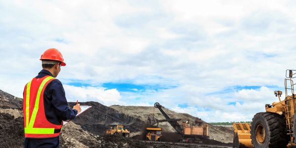 Construction worker inspecting heavy machinery at a mining site.