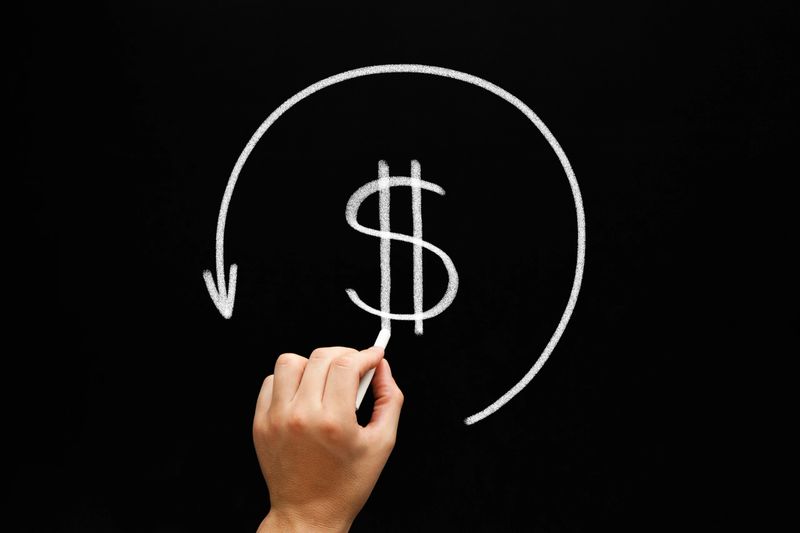 Hand drawing Refund concept - dollar sign in arrow circle with chalk on blackboard. Compensation paid to a customer for returned goods or for over-invoicing. Tax refund - return by the taxation authorities of excess tax paid.