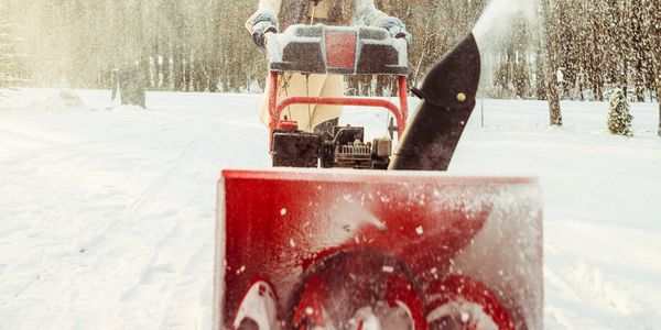 Worker using a snow blower in Big Bear City — professional driveway clearing service.