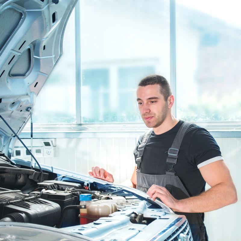 Professional mechanic looks over a car's engine at his workshop
