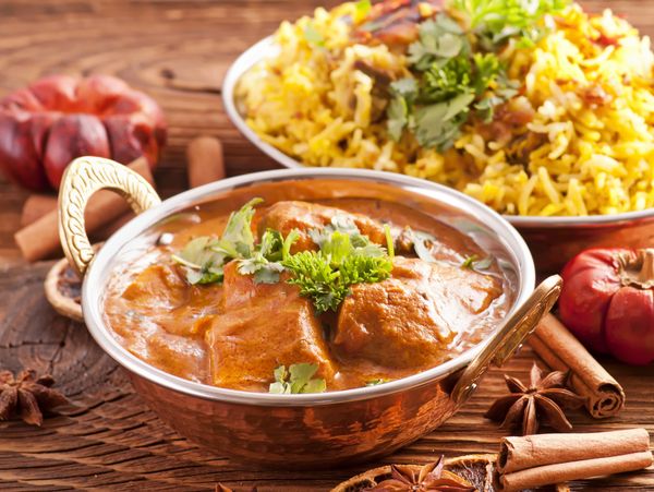 Traditional Indian curry with biryani rice garnished with herbs and spices.