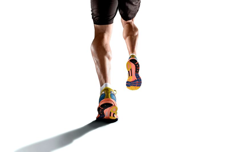 close up view strong athletic legs with ripped calf muscle of young sport man running isolated on white background with copy space in sport fitness endurance and high performance concept