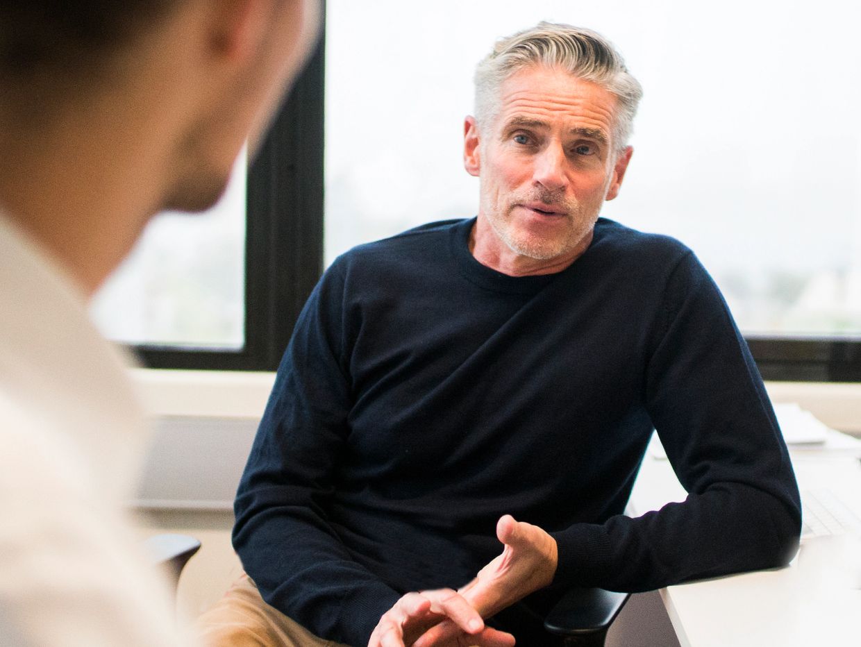 Middle-aged man engaged in a serious conversation in an office setting.
