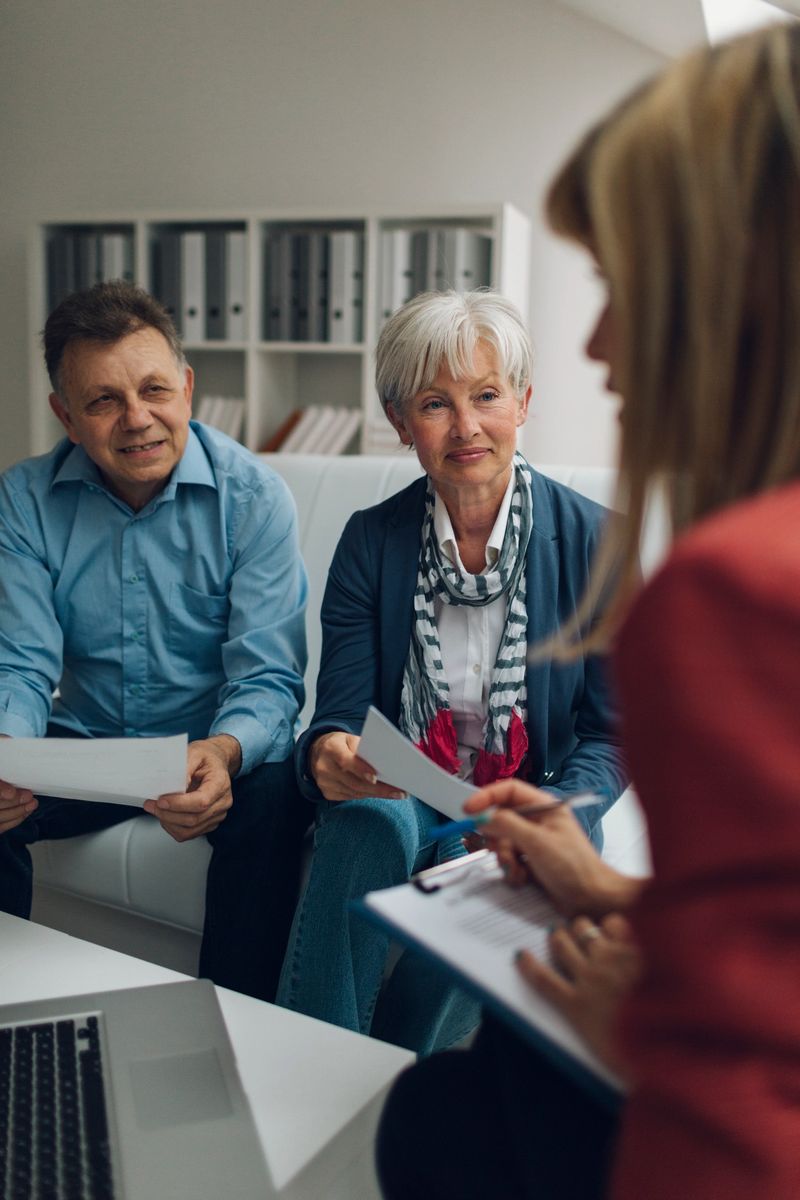 Mature Couple Meeting with Financial Advisor, selective focus to senior man and mature woman listening to financial advisor. She is holding contract and explaining about retirement and insurance options for them.