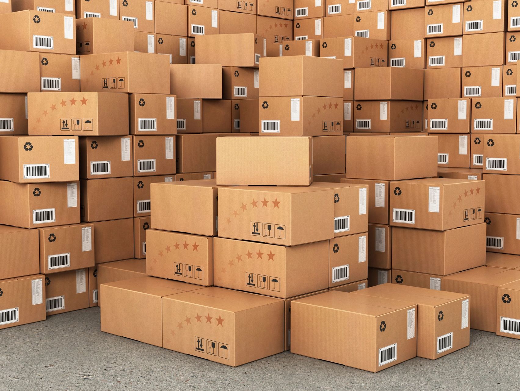 Stacks of cardboard boxes with labels and barcodes in a warehouse.