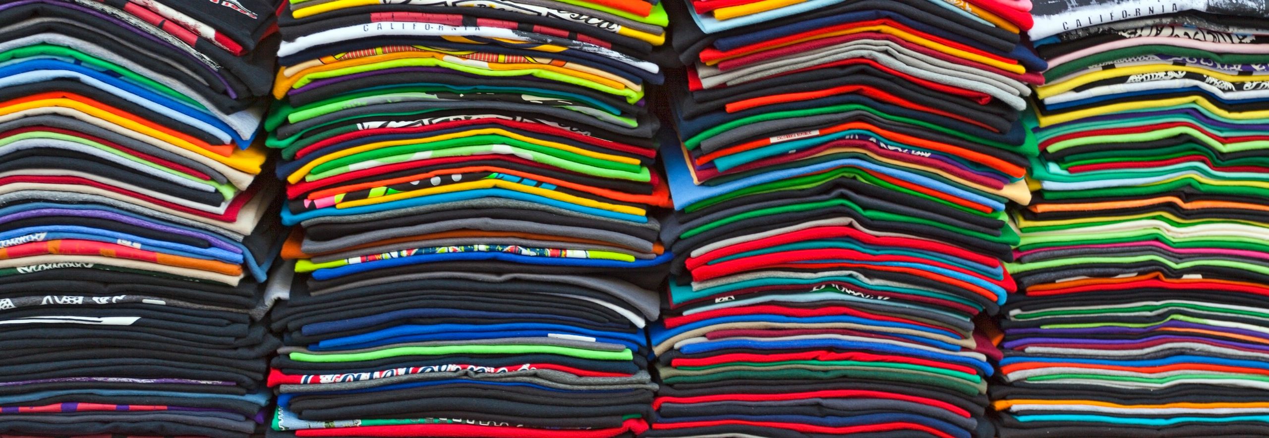 Stacks of colorful folded t-shirts arranged neatly.