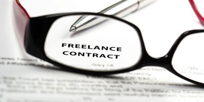 Close-up of glasses and pen on a freelance contract document.