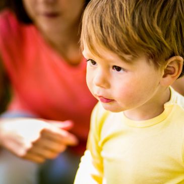 Young child in yellow shirt looking thoughtfully.