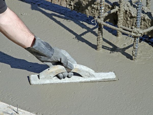 On the ground with a trowel, working on a smooth finish