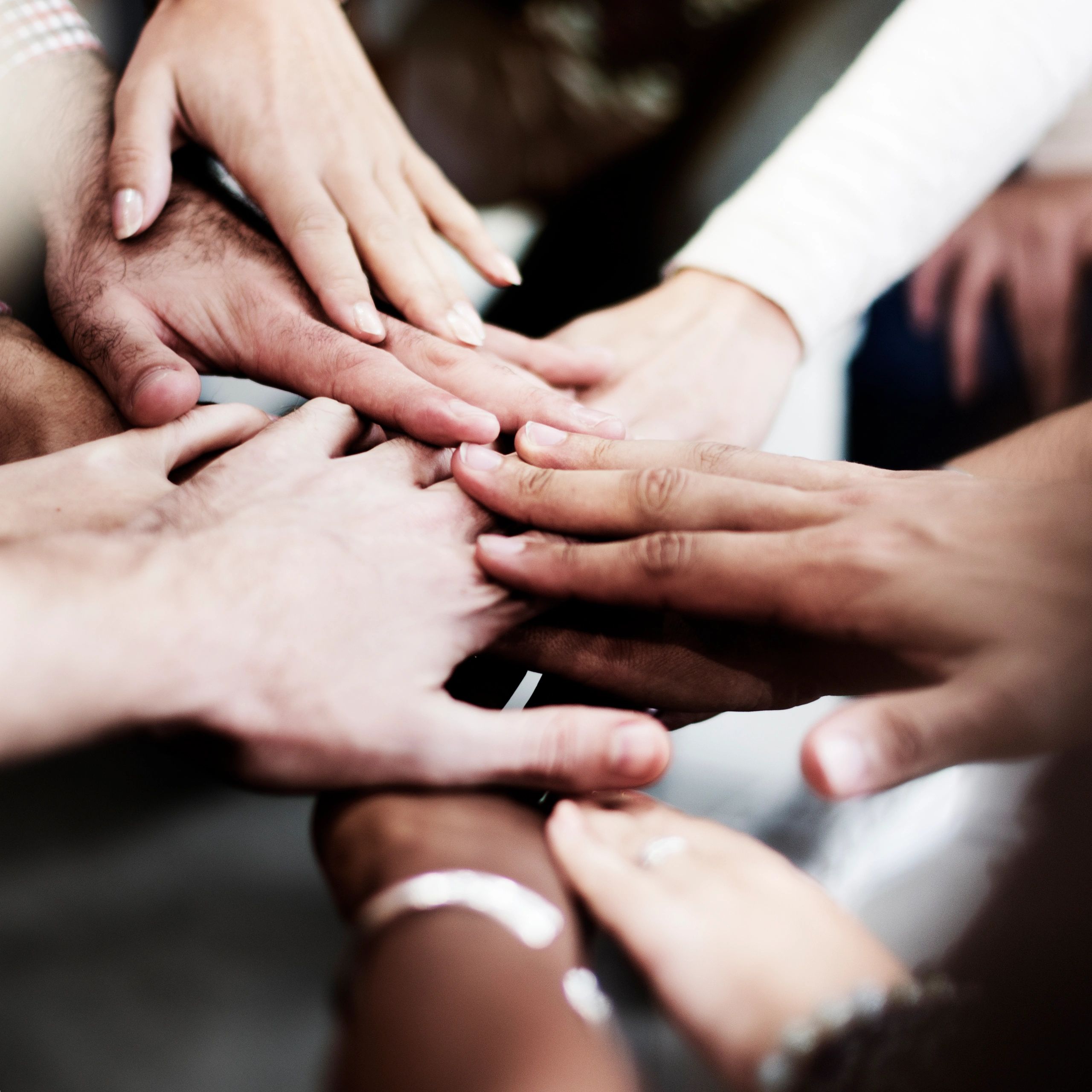Diverse group joining hands in unity and support.