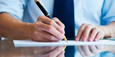 Person writing on paper with a pen.