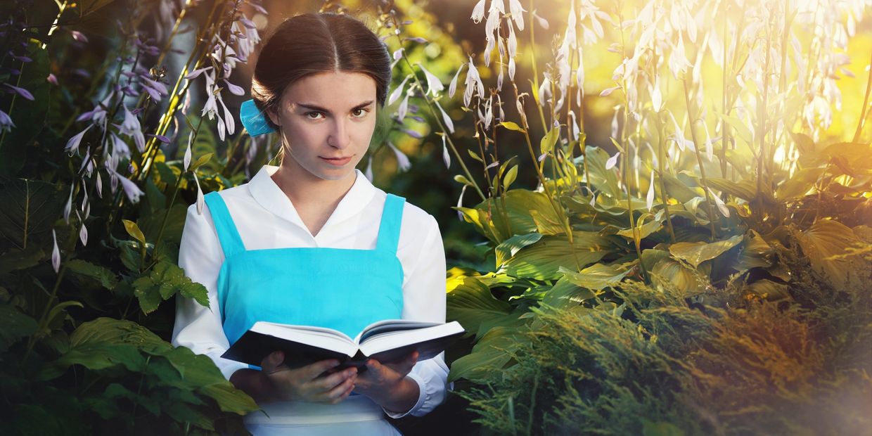 Young woman reading a book in a sunlit garden.