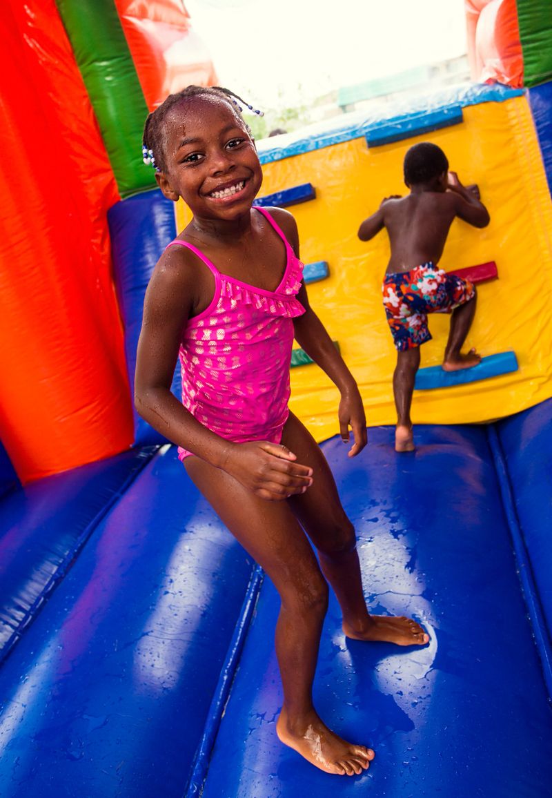 Cute smiling young children playing on an inflatable  bounce house outdoors. Diverse children climbing up and jumping on a bounce house at an outdoor party