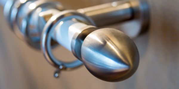 Close-up of a metallic curtain rod finial with rings.