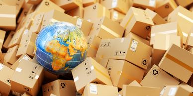 Globe surrounded by numerous cardboard shipping boxes representing global logistics.