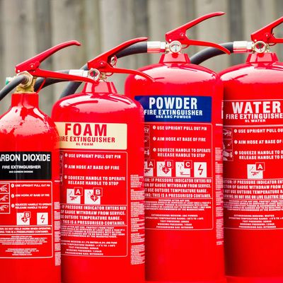 Various types of red fire extinguishers lined up in a row.