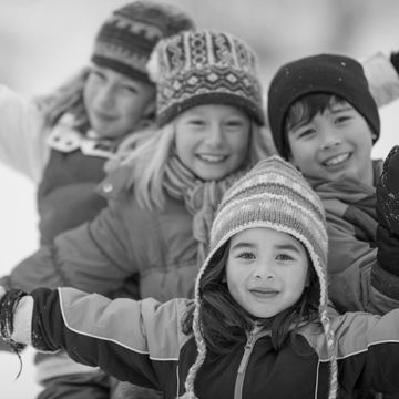 Four children smiling in winter clothes.