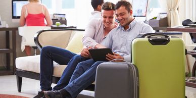 male couple looking at something on a computer in a hotel lobby with luggage