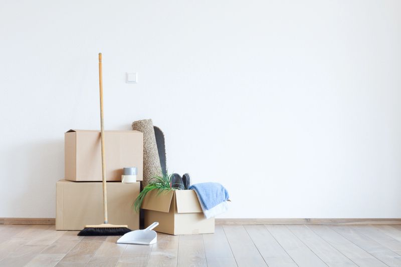 Parade with cardboard, broom, shovel and carpet in front of a white wall on wooden parquet