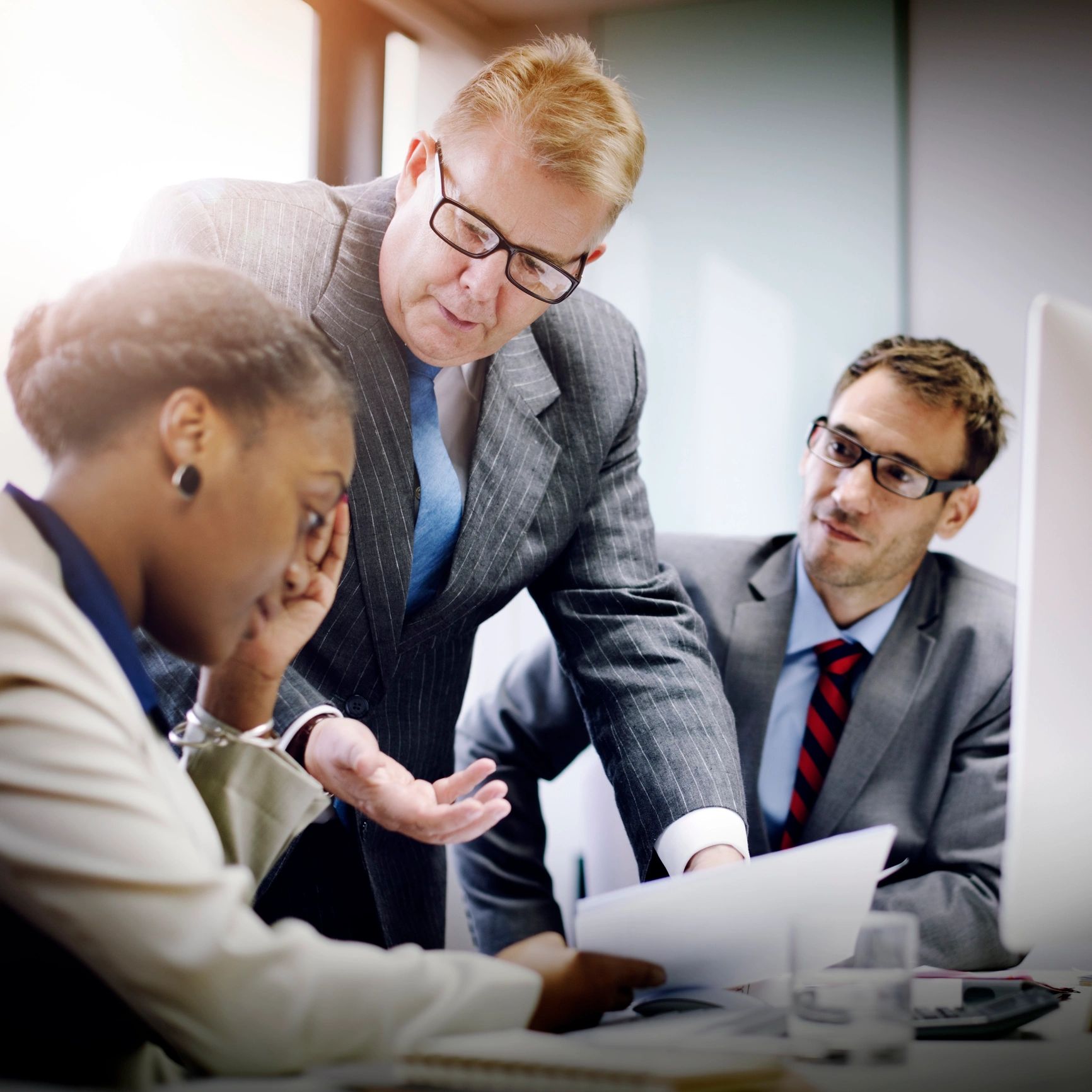 Three professionals engaged in a serious discussion in an office setting.