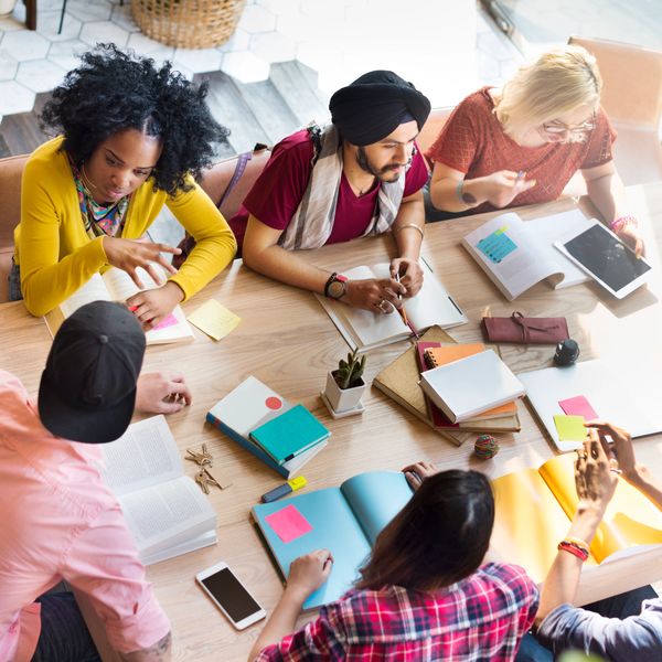 A diverse group of young adults studying and collaborating around a table.