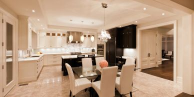 Elegant kitchen and dining area with white and black cabinetry and glass dining table.