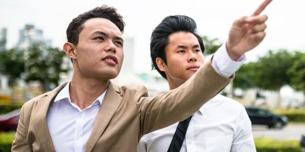 Two businessmen in formal attire, one pointing ahead with determination.