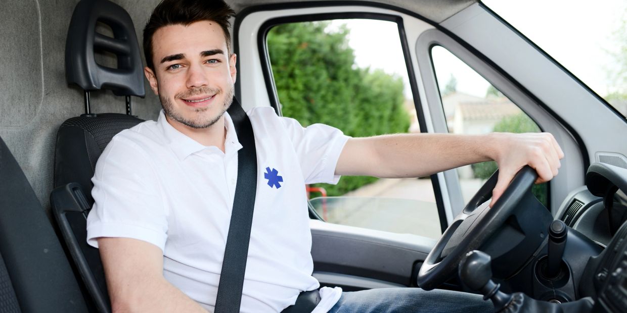 Young paramedic driving a vehicle smiling.