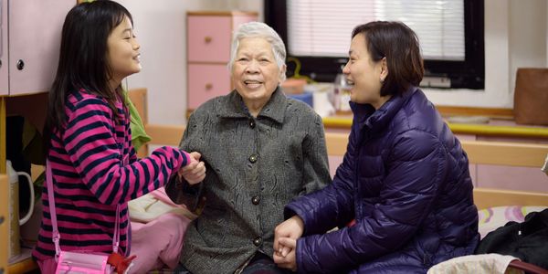 Three generations of women joyfully holding hands indoors.