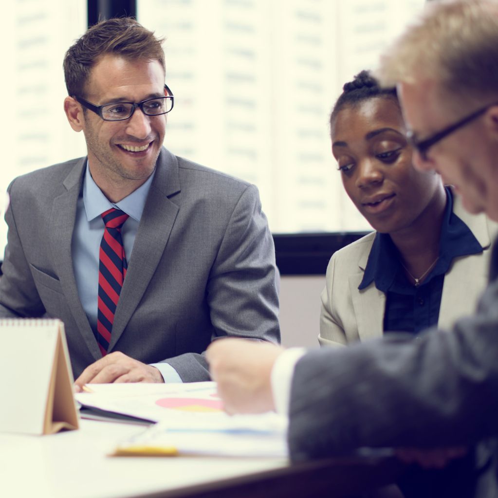 Three professionals engaged in a business meeting with documents.