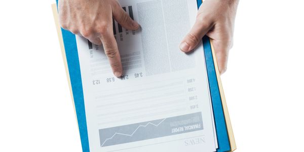 Person pointing at financial report charts on documents.