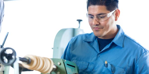 Man working on a lathe machine wearing safety glasses.