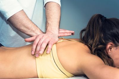Person receiving a chiropractic adjustment in the mid-back.