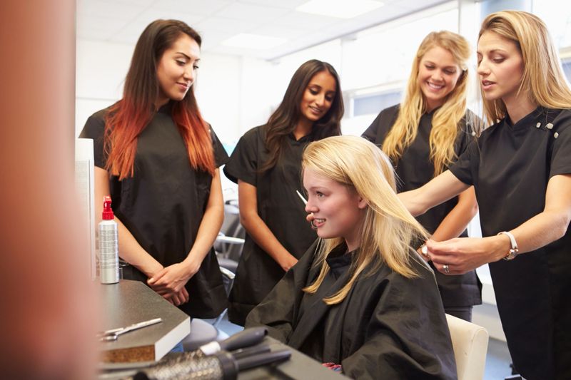 Teacher Helping Students Training To Become Hairdressers
