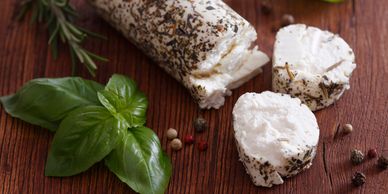 Fresh goat cheese with herbs and basil leaves.