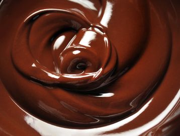 Smooth, glossy melted chocolate swirling in a rich spiral.