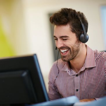 Smiling customer service advisor with a headset looking at a computer