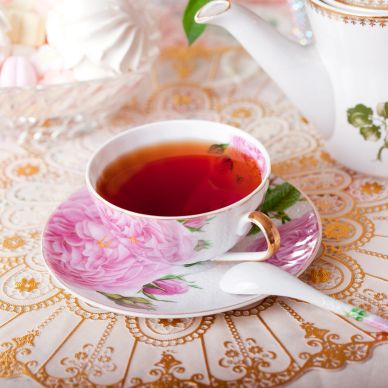 Tea in a floral teacup with a matching saucer and porcelain spoon.